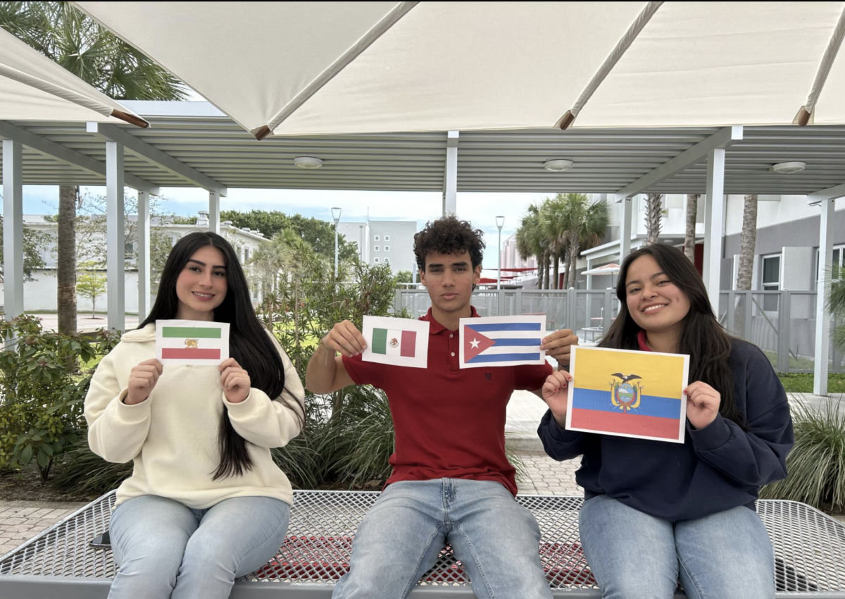 Los estudiantes posan con las banderas que representan tres historias únicas de su experiencia hasta ahora.